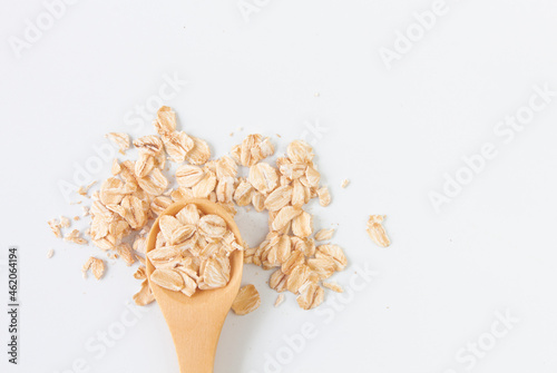 Top view of dry rolled oatmeal in wooden spoon isolated on white background.