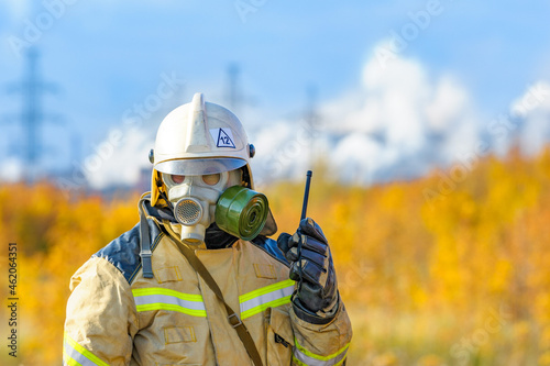 Firefighter rescuer in a protective suit and white helmet, fighting a fire at a chemical plant. Operation to extinguish the fire and eliminate the leakage of ammonia.