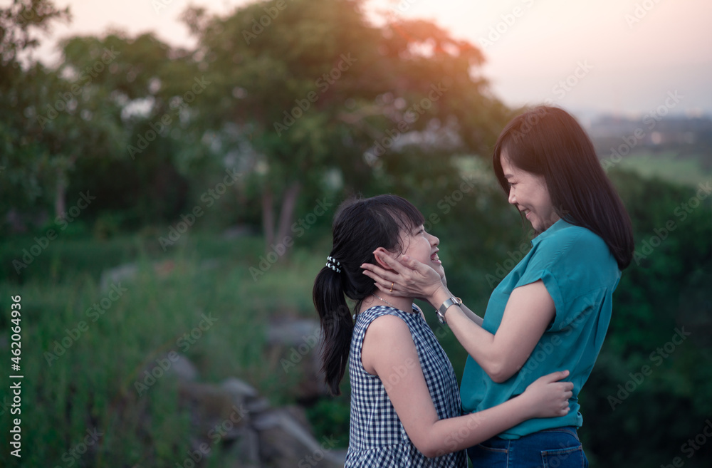 Mother and daughter are hugging and having fun outdoor in green nature with sunset Mother and daughter are hugging and having fun outdoor in green nature with sunset