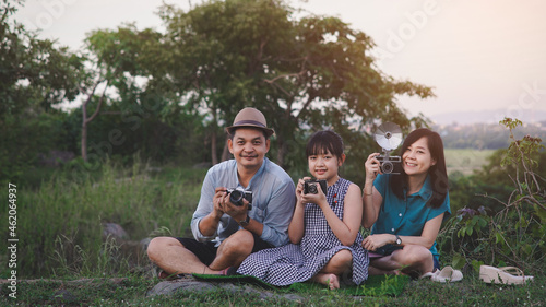 Vintage family of photographers are happily taking pictures with the film camera in green nature and beautiful sunset