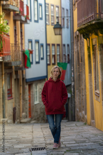 A woman in a hoodie walks through an old Portuguese town.