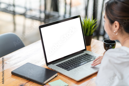 Slika na platnu Side view of a businesswoman working on a laptop blank white screen at office