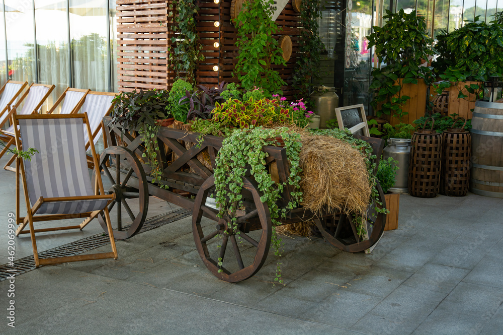 an old wooden cart with flowers and hay as a decoration and decoration of the entrance to the restaurant