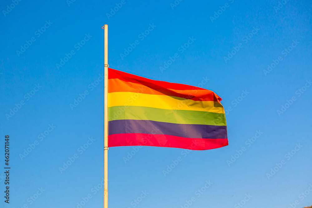 Rainbow flag LGBT movement symbol against blue sky background Rainbow flag LGBT movement symbol against blue sky background