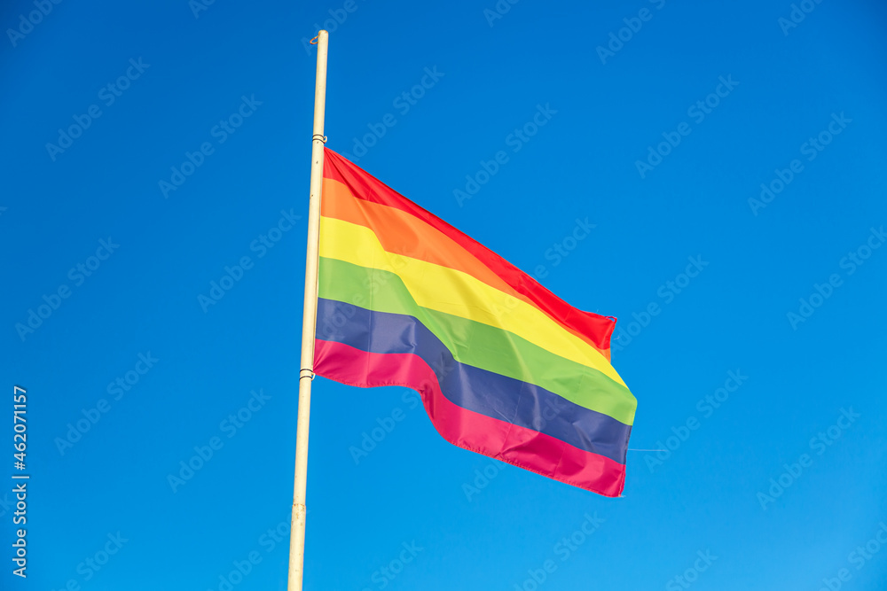 Rainbow flag LGBT movement symbol against blue sky background Rainbow flag LGBT movement symbol against blue sky background