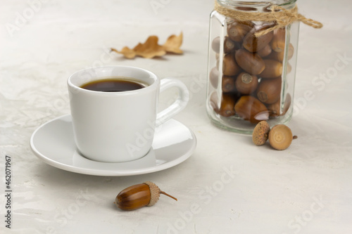 Acorn coffee in a white cup and acorns in a glass jar. Healthy no caffeine beverage