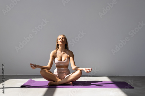 young woman practicing yoga in the lotus position on white background
