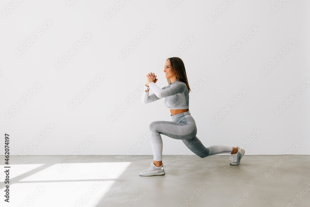 Portrait of a fitness woman doing squats isolated over white background Portrait of a fitness woman doing squats isolated over white background