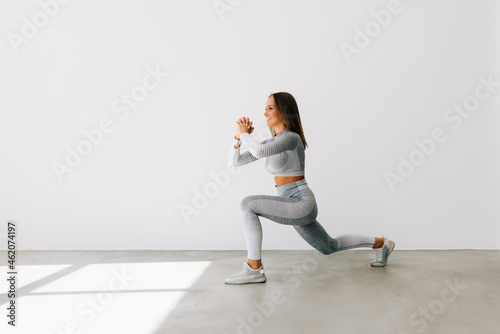 Portrait of a fitness woman doing squats isolated over white background