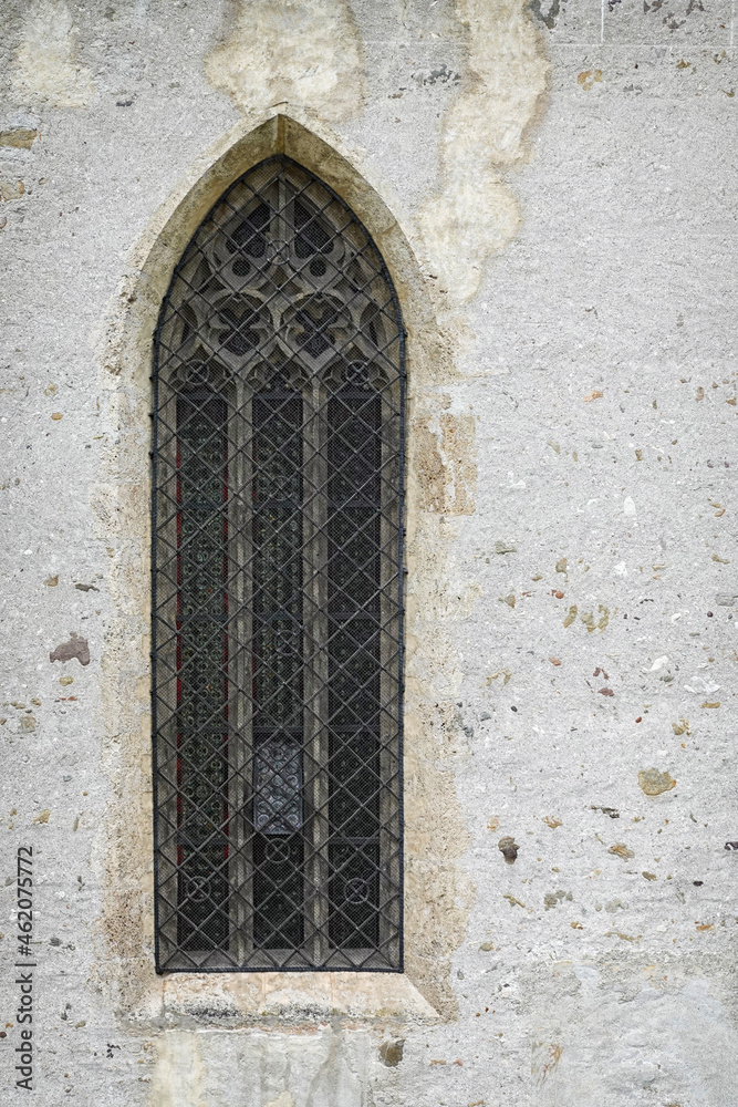 Window with stained glass windows on the old church. High arched window in the Church of Fiera di Primiero, Italy, Europe 