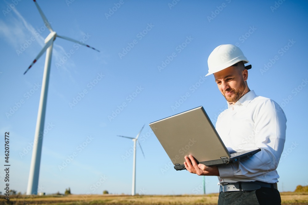 Young engineer man looking and checking wind turbines at field Young engineer man looking and checking wind turbines at field
