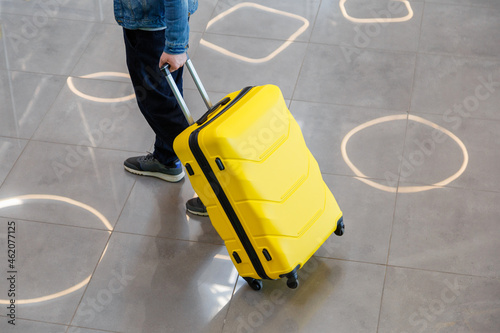 Large yellow suitcase luggage in male hands on the way to the train station. A man walks through the airport and carries a yellow large suitcase luggage