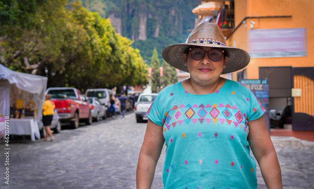 Adult Latina woman, smiling at the camera, standing in the middle of the street. Latina tourist