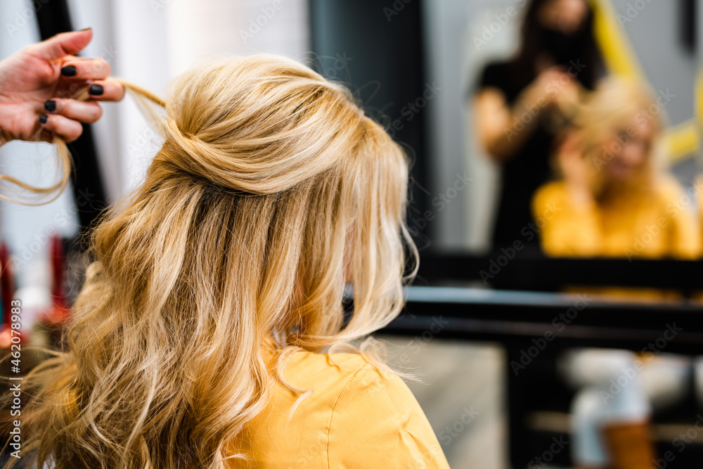 Naklejka premium Beautiful hairstyle of blond middle-aged woman in modern hair salon...