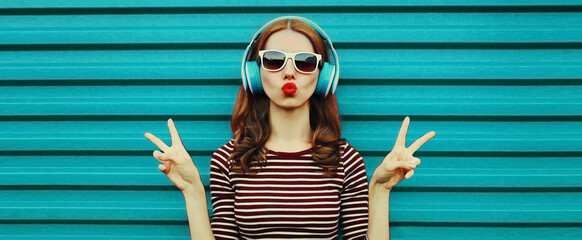 Portrait of cheerful young woman with headphones listening to music on a colorful blue background