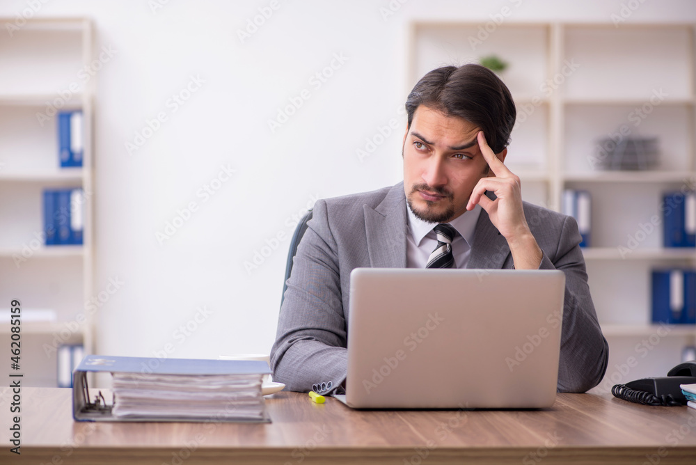 Young attractive male employee sitting at workplace Young attractive male employee sitting at workplace
