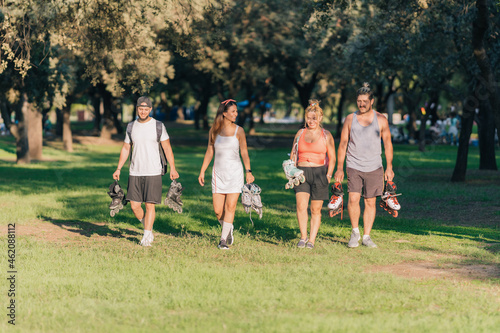 Group of people walking in a park with inline skates in their hands