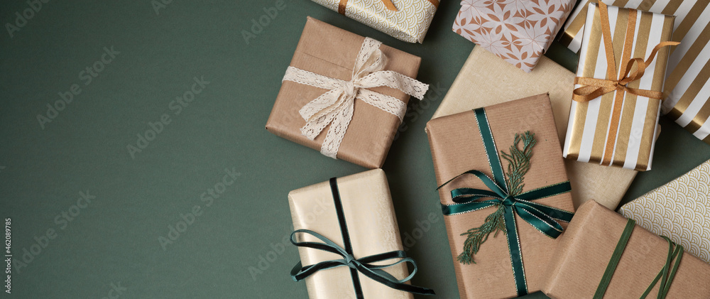 Christmas background with gift boxes over green backdrop. Xmas celebration, preparation for winter holidays, secret Santa, advent calendar concept. Festive banner, website header, top view, flat lay - obrazy, fototapety, plakaty 