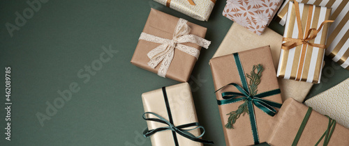 Christmas background with gift boxes over green backdrop. Xmas celebration, preparation for winter holidays, secret Santa, advent calendar concept. Festive banner, website header, top view, flat lay photo