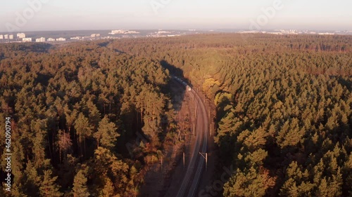 Eelectric commuter train travels through the autumn forest. Aerial view. photo