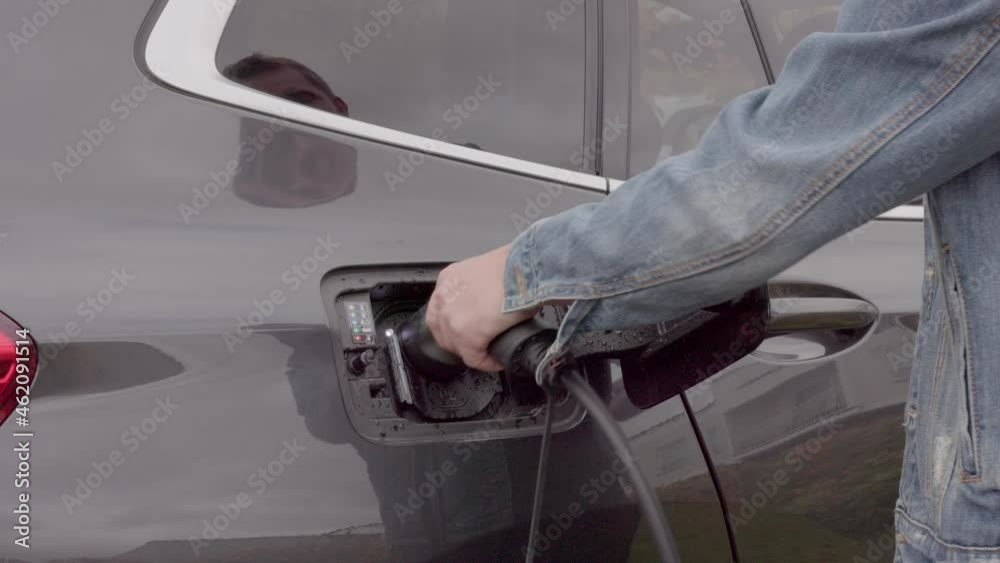 Close up view of man unplugging charging cable to charging station for electric car. Sweden. Close up view of man unplugging charging cable to charging station for electric car. Sweden.