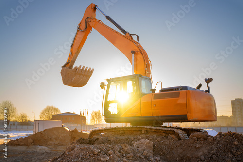 Wallpaper Mural Orange color excavator on the construction site at sunset. Industrial image Torontodigital.ca
