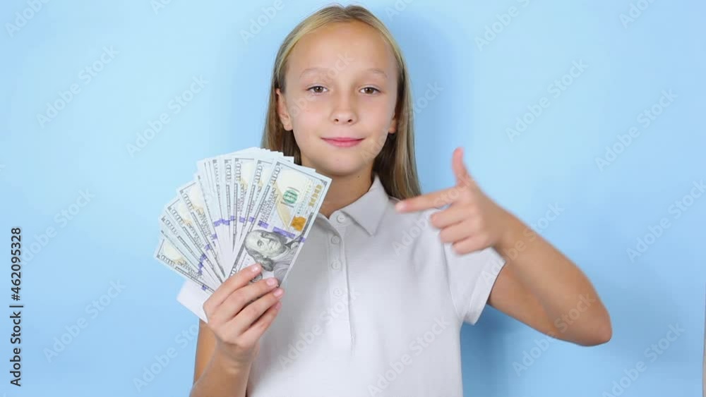 Girl holding money in hands on a blue background close up Girl holding money in hands on a blue background close up