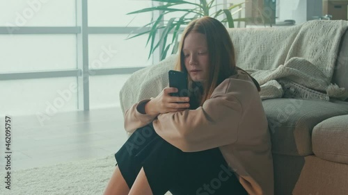 A Depressed Teenage Girl Looks at the Phone, is Sad, Afraid of Bullying On Social Networks. Stress, Online Bullying, Cyberbullying, Psychological Abuse.