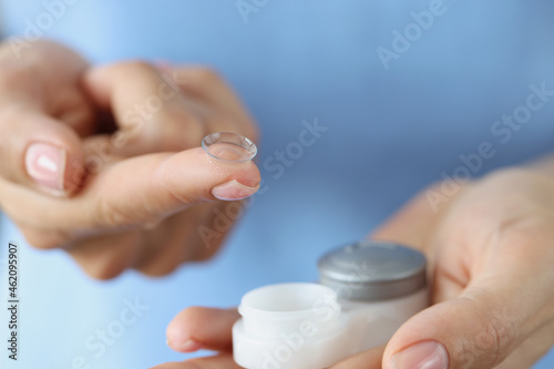 Soft contact lens on finger and storage box closeup
