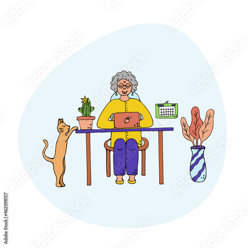 Happy cute old woman working and sitting at desk with laptop at home.