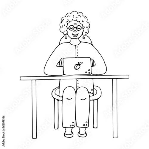 Happy cute old woman working and sitting at desk with laptop at home.