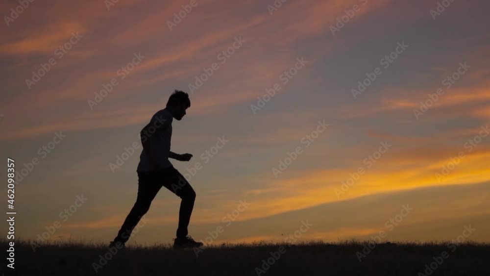 Silhouette shot of an Indian man running in front of the sun during the sunset. Man takes a jog before the sunrise. Athlete working out in the early morning and going for a morning jog. Health concept Silhouette shot of an Indian man running in front of the sun during the sunset. Man takes a jog before the sunrise. Athlete working out in the early morning and going for a morning jog. Health concept