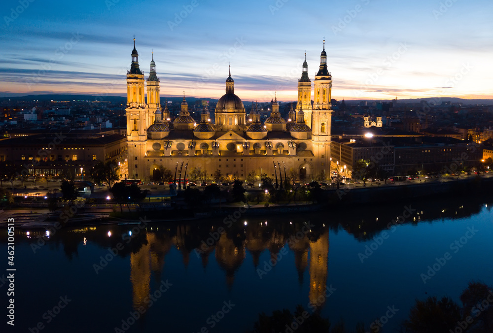 Aerial view of lighted Roman Catholic Basilica Our Lady of Pillar on background of Zaragoza cityscape and Ebro river at dusk, Spain..