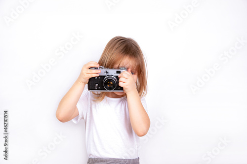 A little girl holds a vintage camera in her hands and takes pictures.