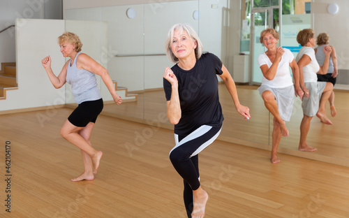 Positive aged woman practicing vigorous dance movements in group dance class .