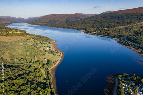Aerial drone view of a beautiful, tranquil Scottish loch in the early morning sunshine (Loch Eil, Fort William)