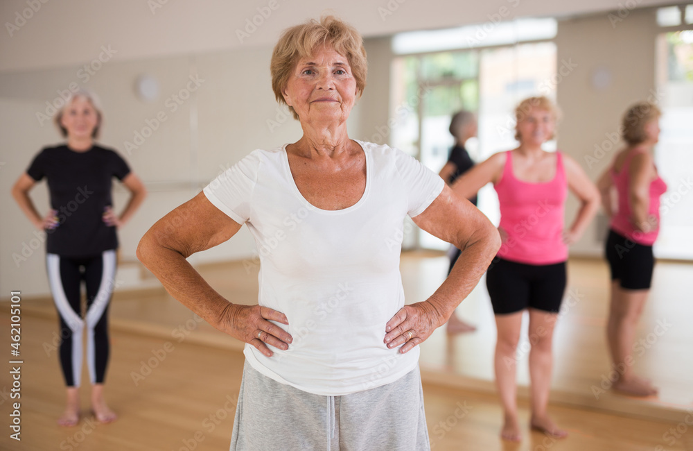 Portrait of a mature woman and people engaged in dancing in the studio, doing a warm-up at the beginning of the class