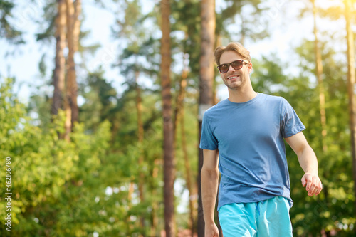 A young man in a blue tshirt and sunglasses near swimming pool © zinkevych