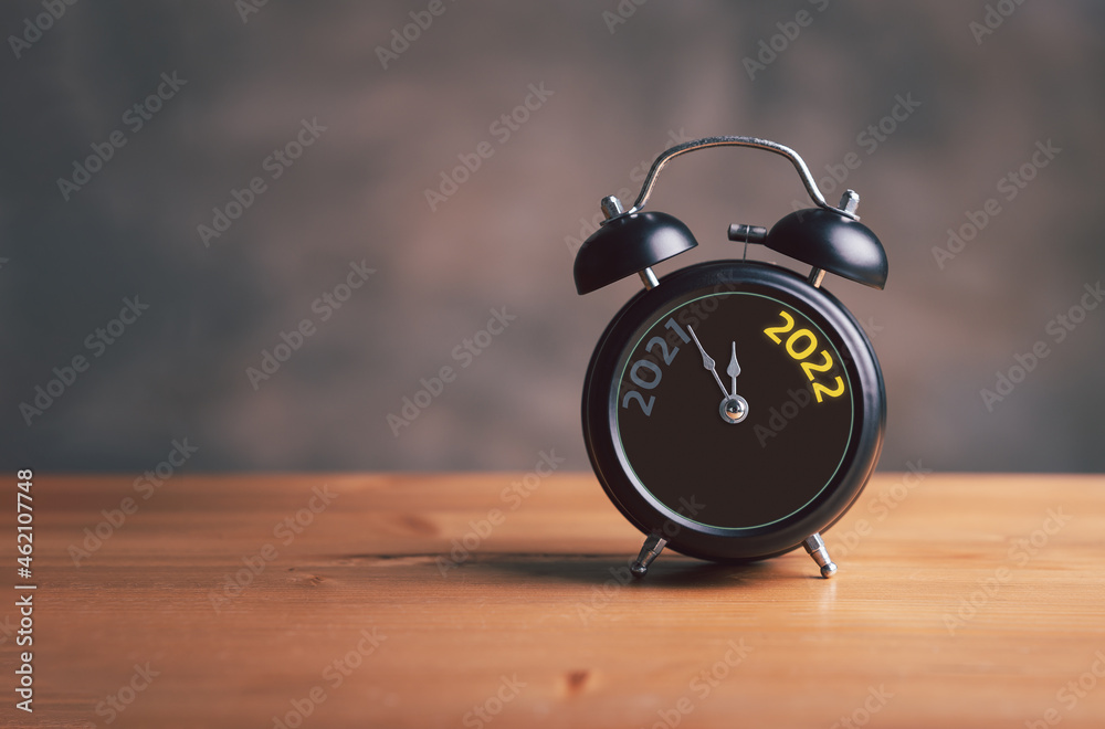 2021 and 2022 on black alarm clock on wooden table with copy space , Merry Christmas and Happy new year concept.