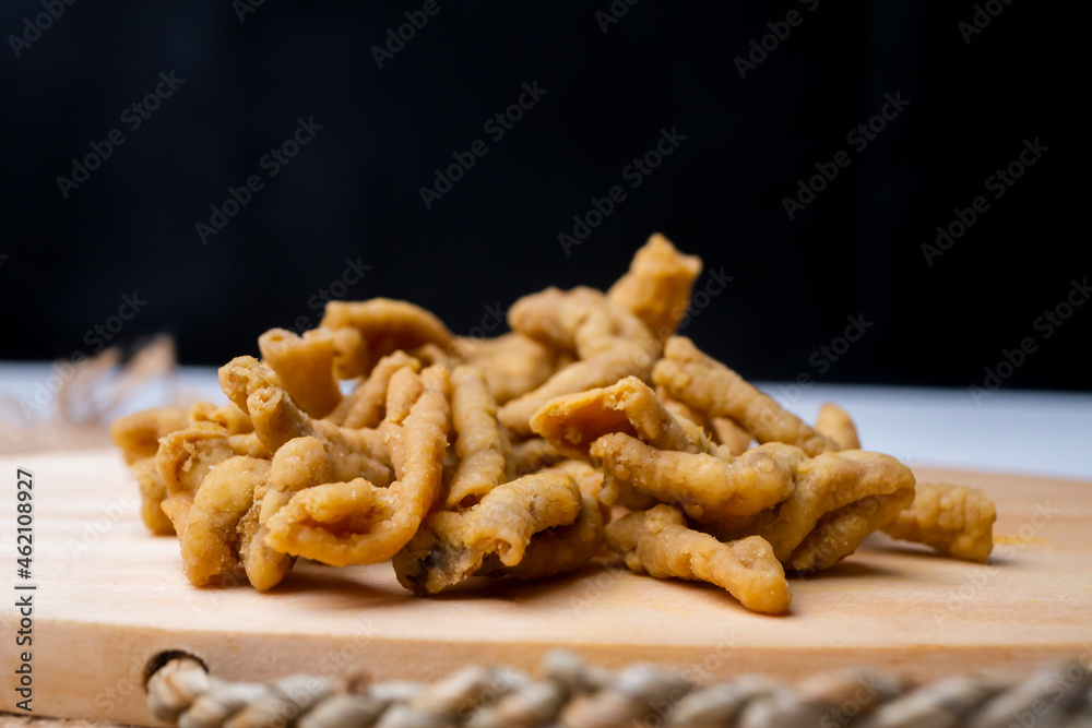 Close up view of kripik keripik usus ayam or gut chicken fried snack fritters crackers. traditional menu from Indonesia on wooden cutting board