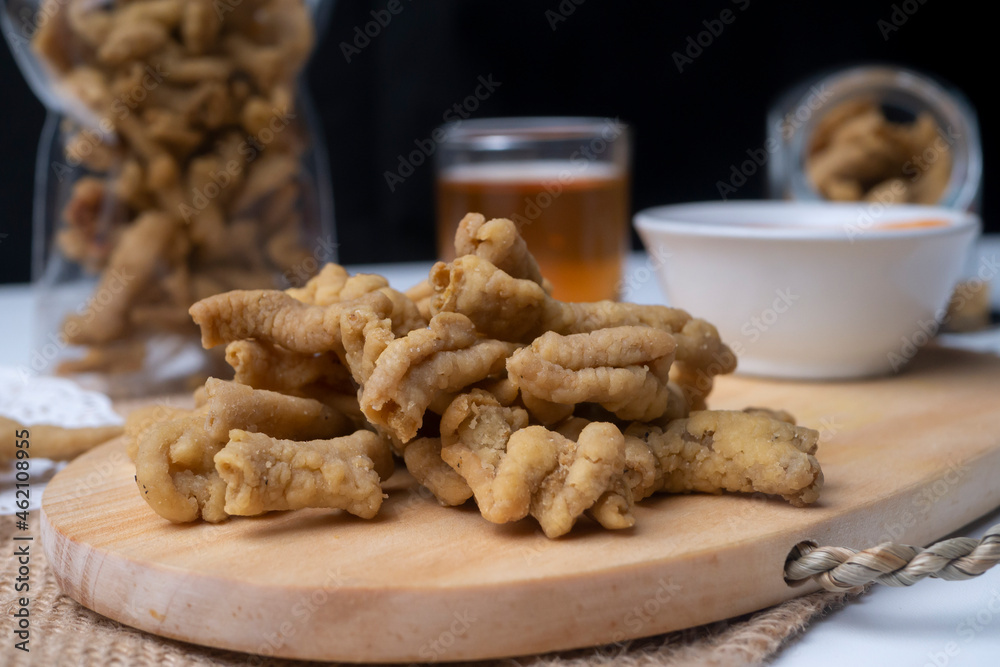 Close up view of kripik usus ayam or gut chicken fried snack fritters crackers. traditional menu from Indonesia, on wooden cutting board