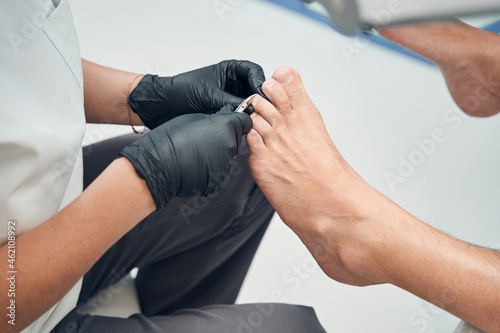 Pedicure master cutting man toenails in cosmetology salon