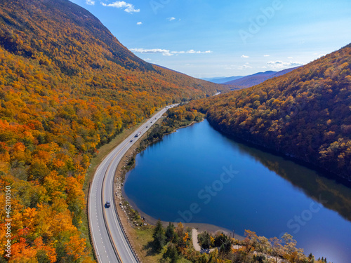 aerial view of road near lake in autumn forest and mountain