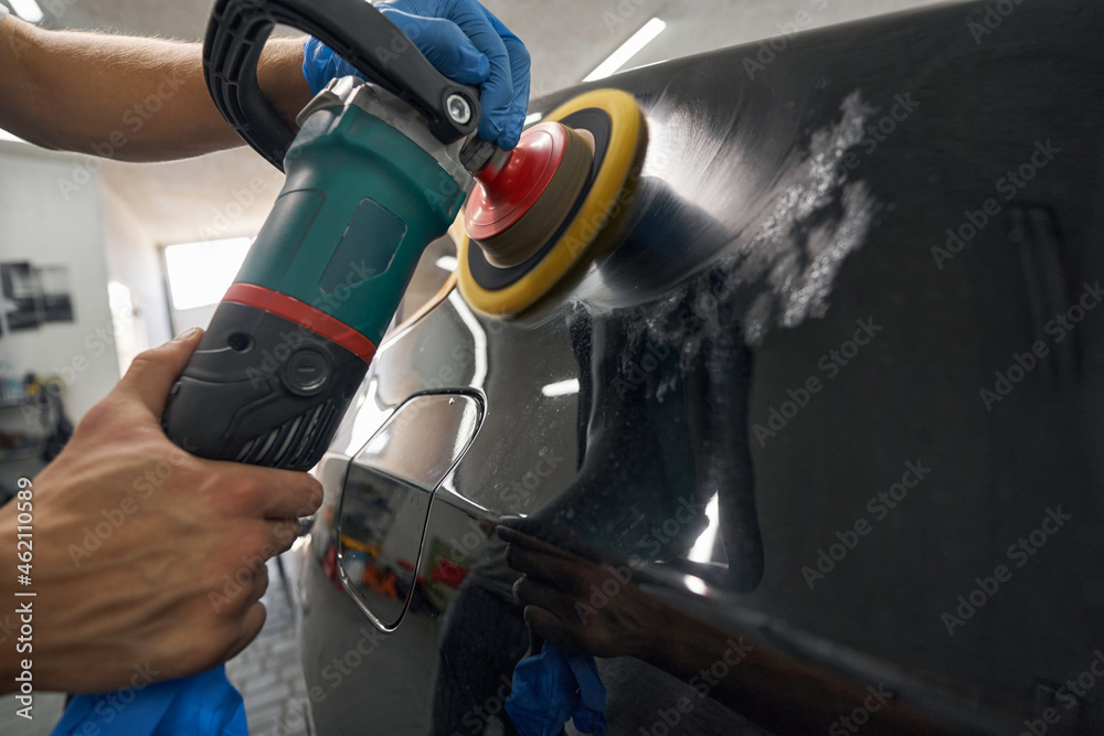 Car detailing studio worker polishing car varnish with electric polisher Car detailing studio worker polishing car varnish with electric polisher