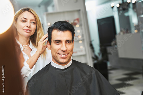 Professional hairdresser examining customer hair in salon