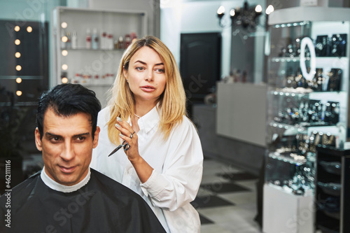 Hairdresser bringing scissors close to customer head