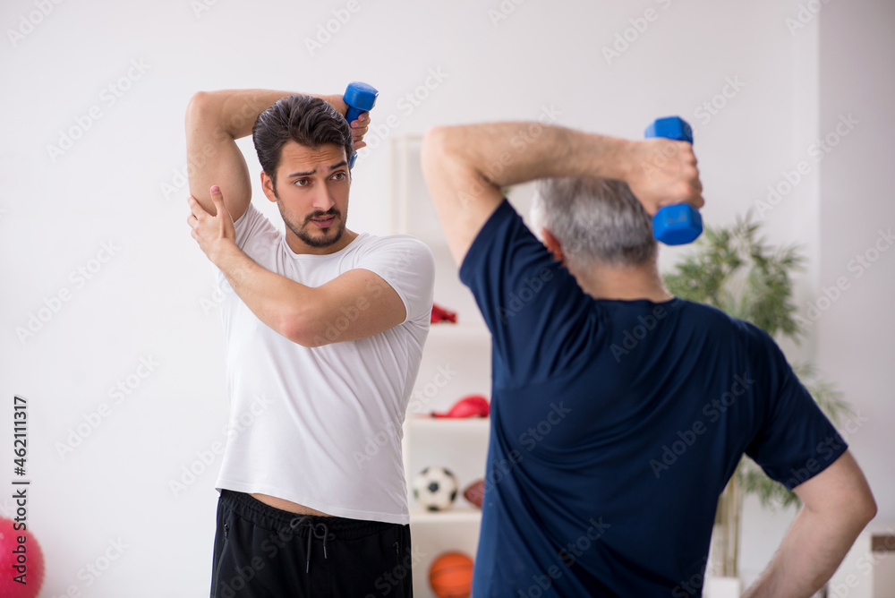 Young male instructor and old man doing sport exercises Young male instructor and old man doing sport exercises