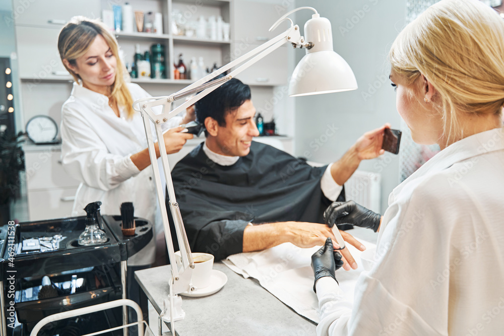 Fototapeta premium Female with file grinding nails of client with phone