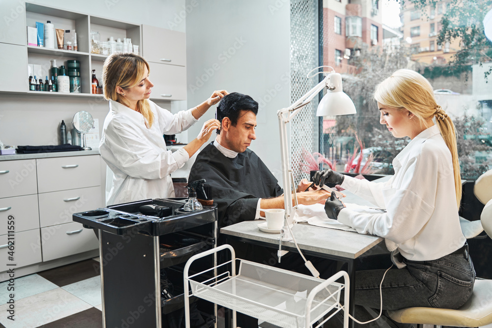 Obraz premium Beauty parlour visitor with smartphone having his hair cut