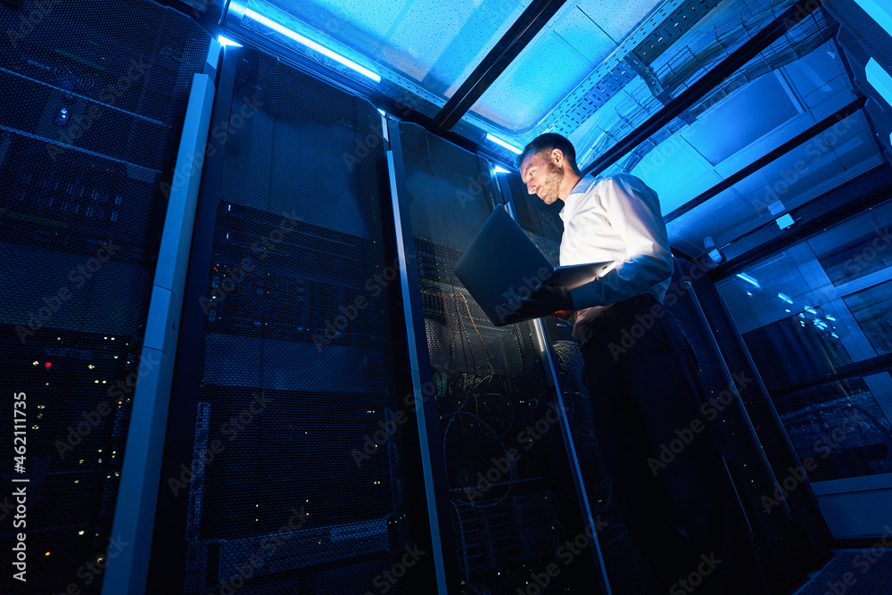 Fototapeta premium Network administrator using laptop while doing computer equipment checkup
